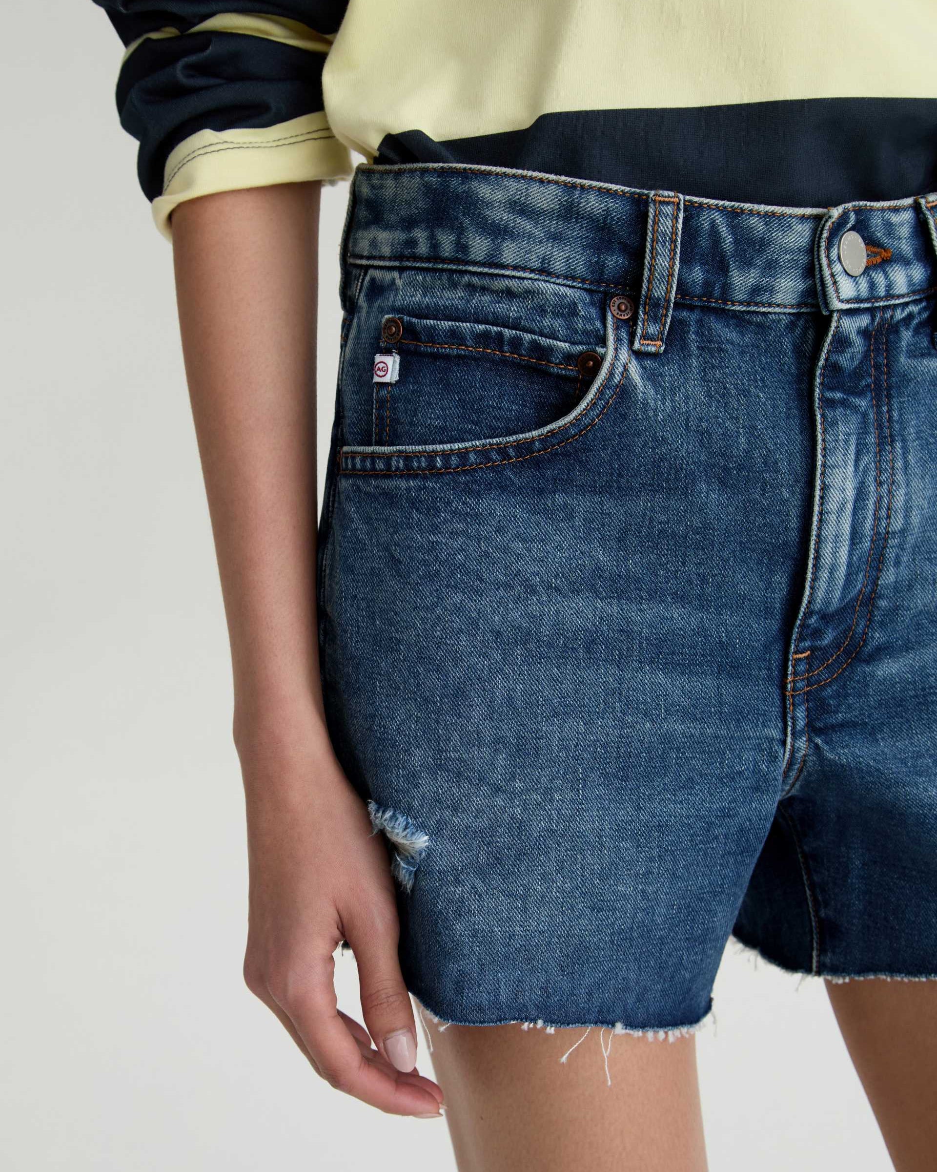 Person wearing blue denim shorts on a plain background