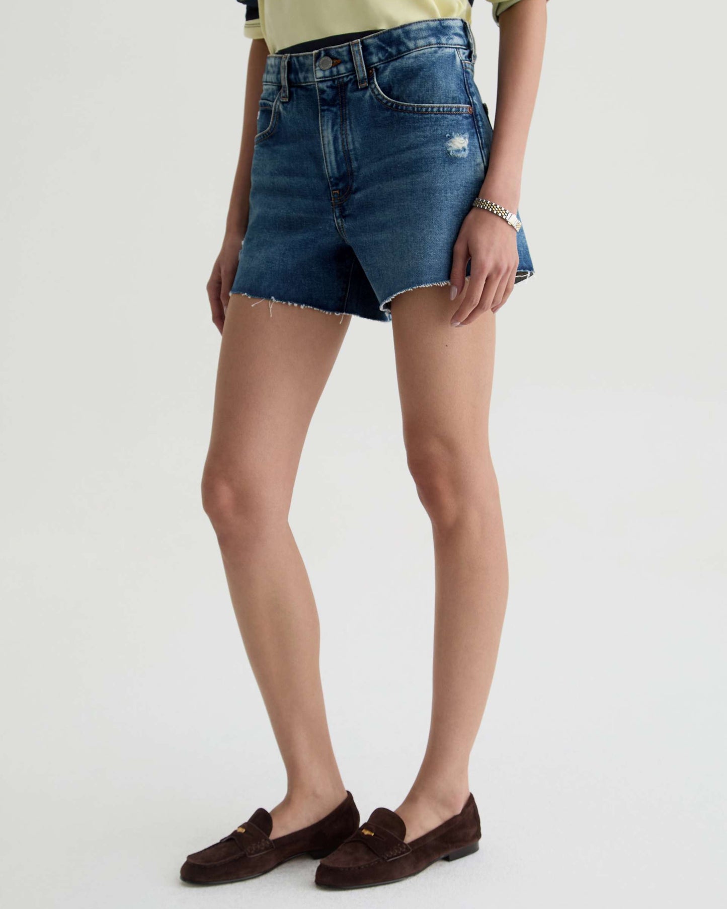 Person wearing blue denim shorts on a plain background