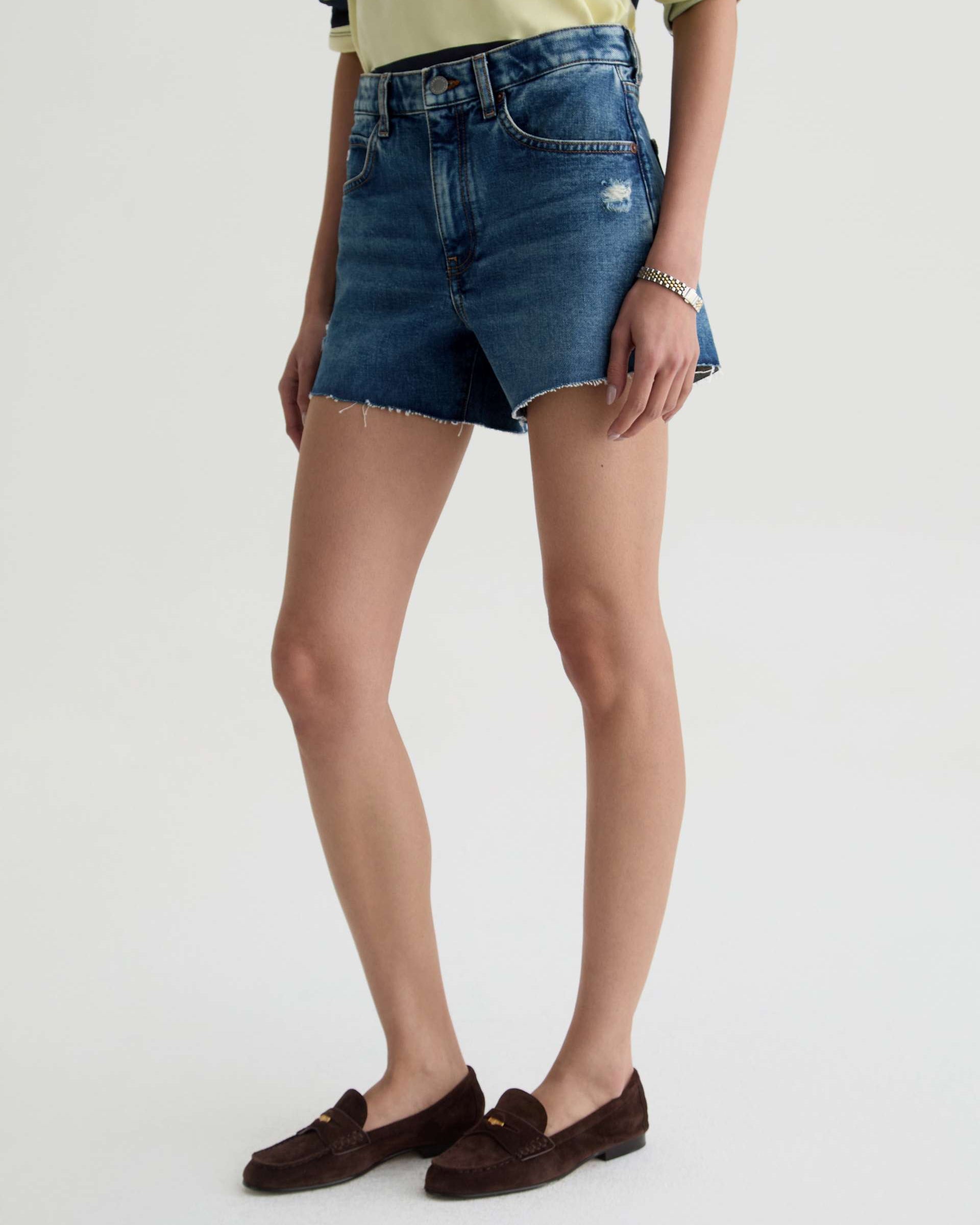 Person wearing blue denim shorts on a plain background