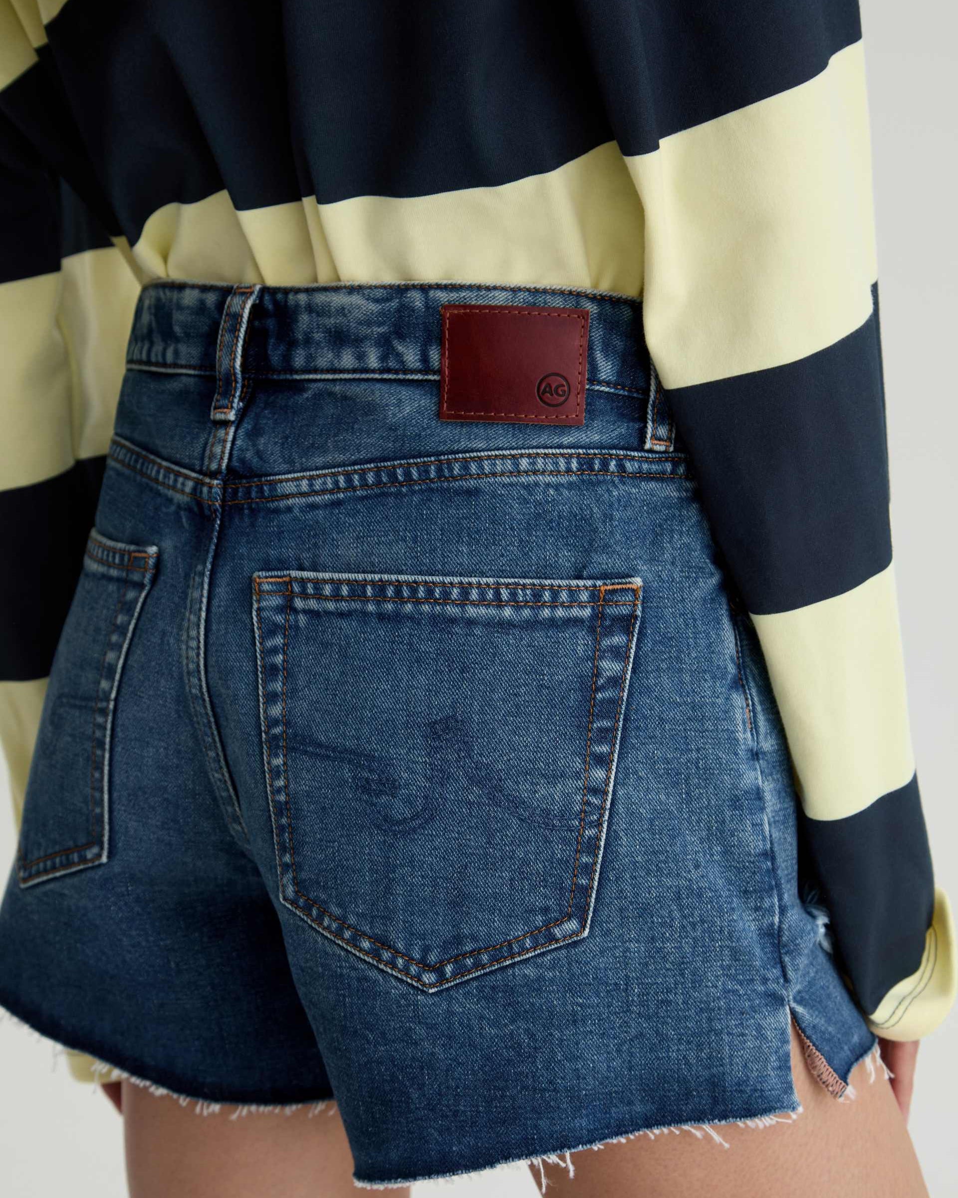 Person wearing a striped shirt and denim shorts with a visible brand logo.