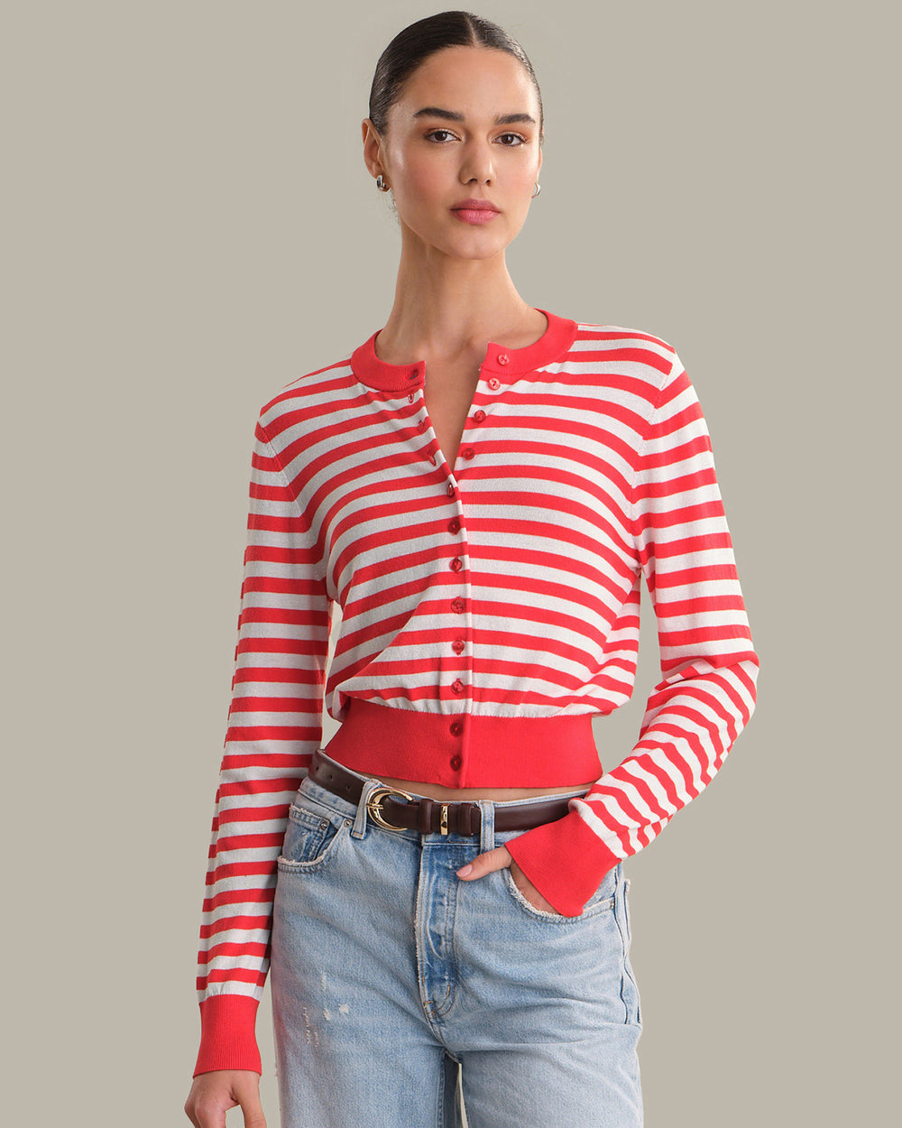 Woman wearing a red and white striped shirt with blue jeans on a gray background