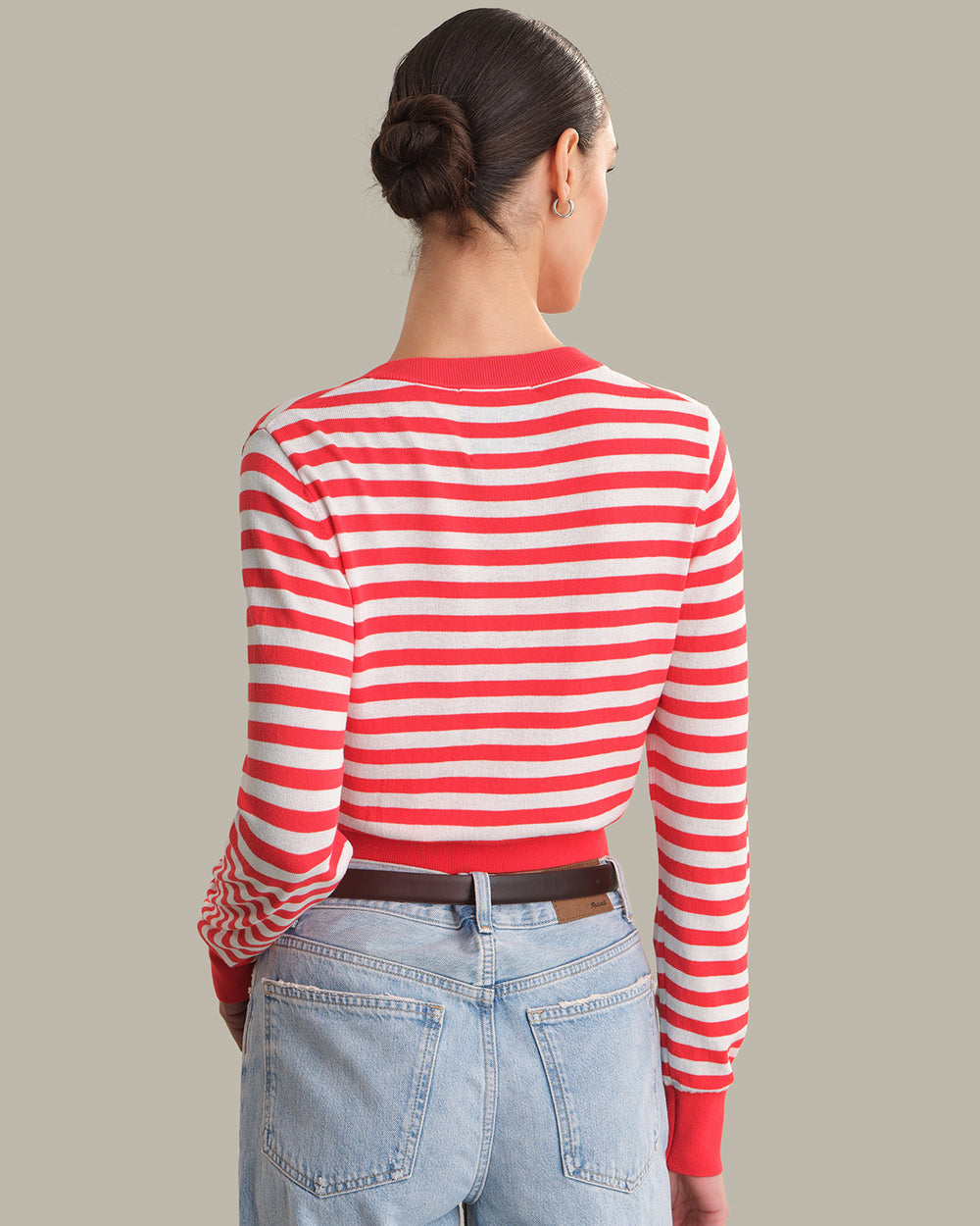Person wearing a red and white striped shirt with blue jeans on a plain background