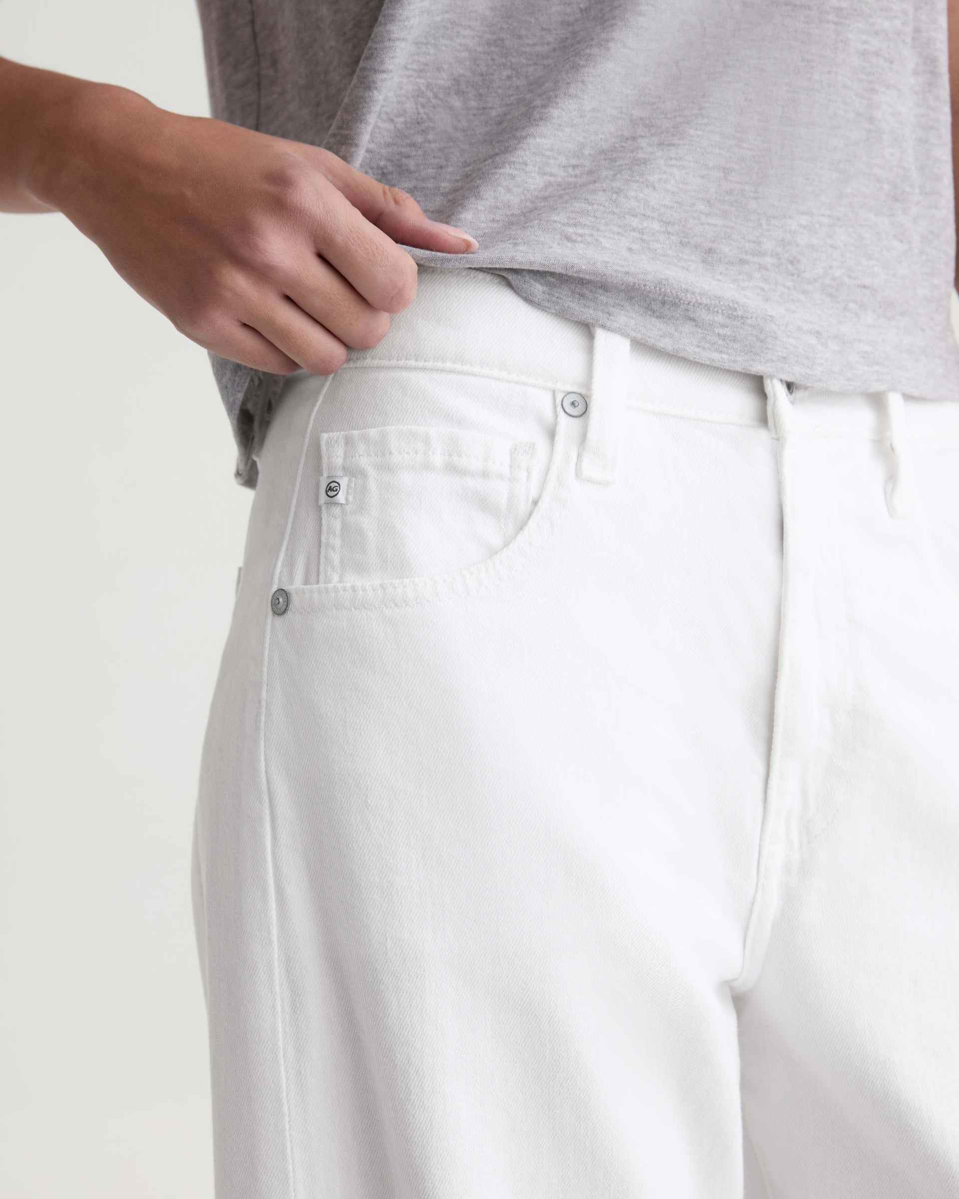 Person wearing white pants with a plain background