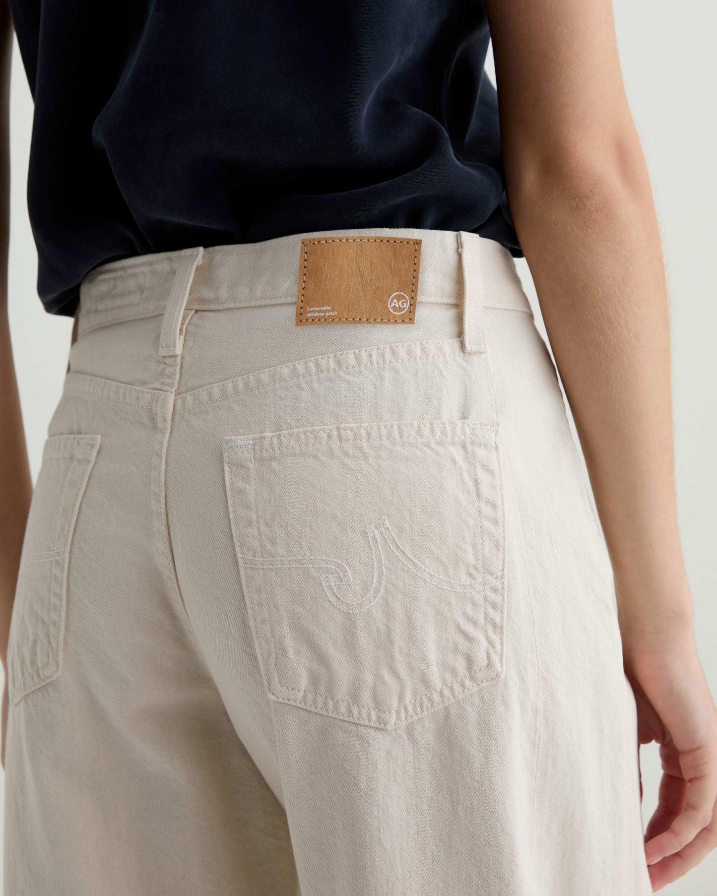 Beige pants with a brand patch on a plain background