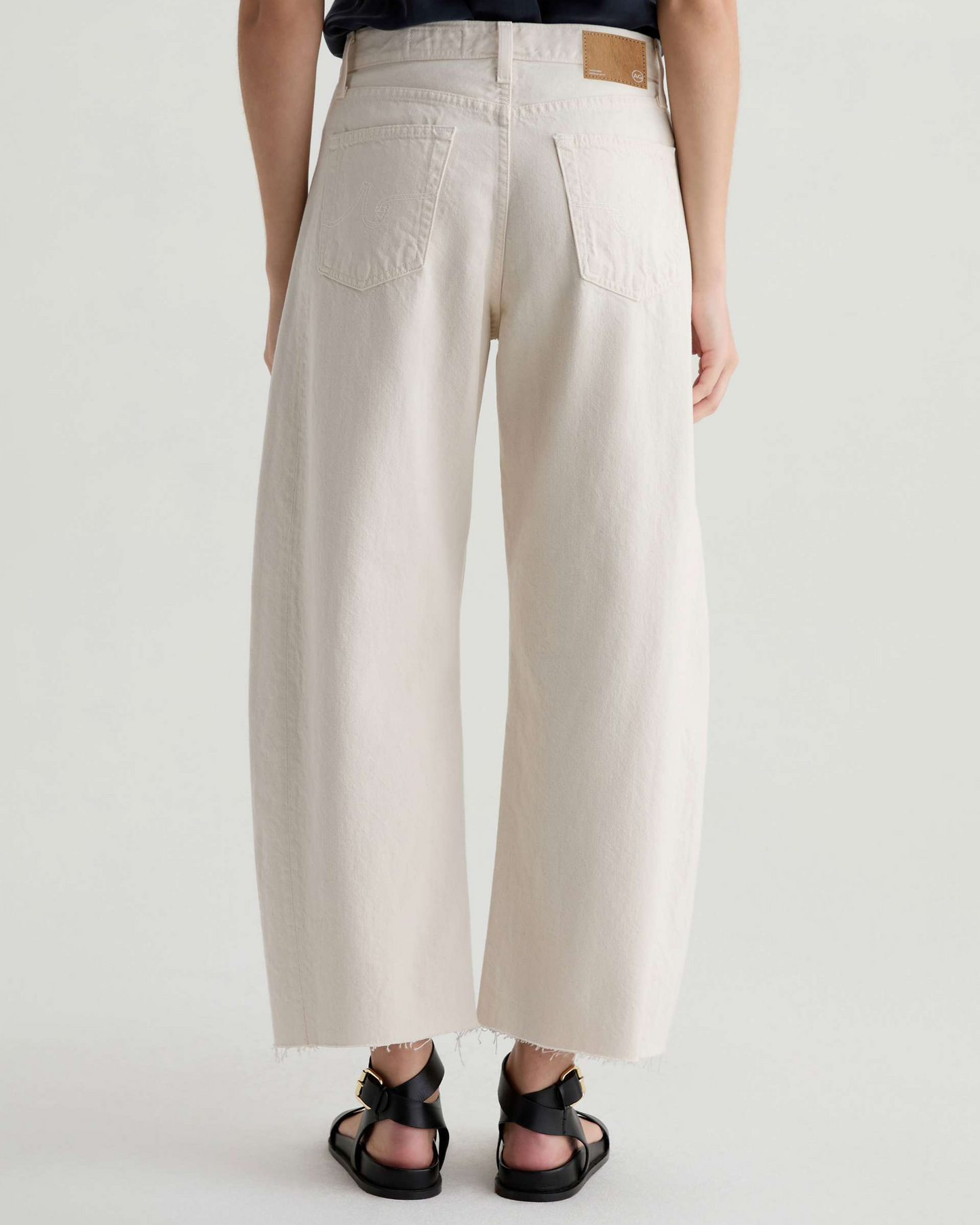 Person wearing beige wide-leg pants on a white background