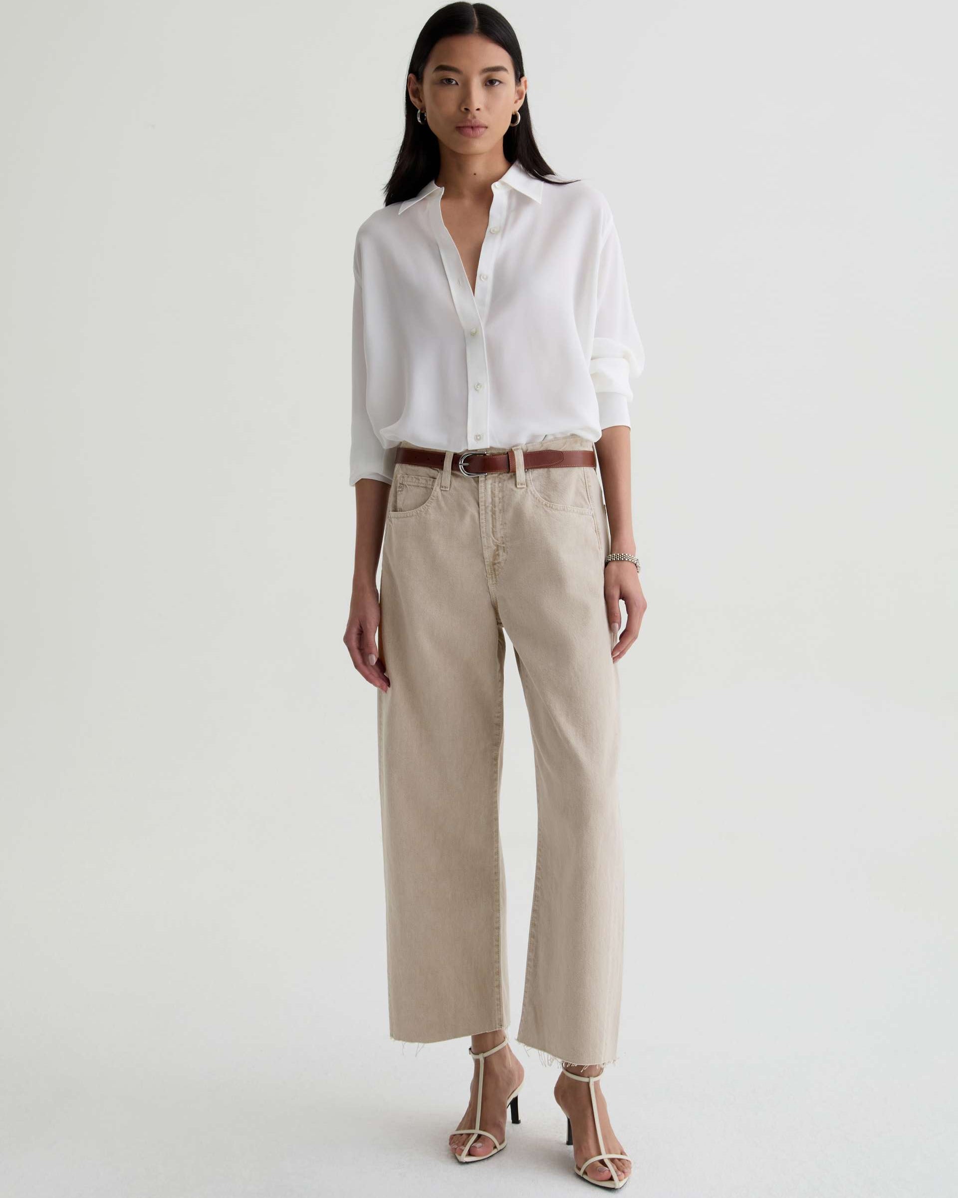 Woman wearing a white shirt and beige pants on a white background