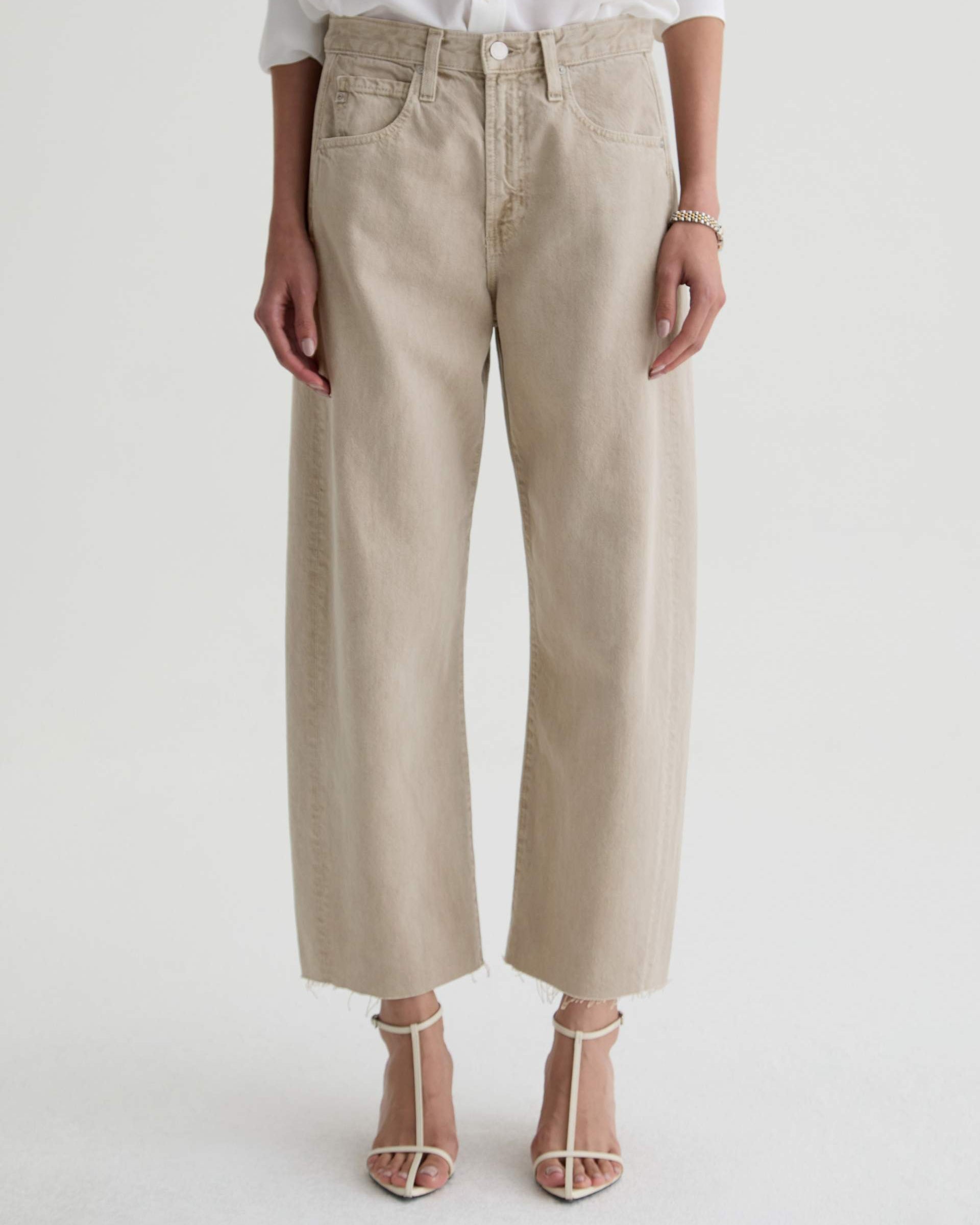 Person wearing beige pants and a white shirt on a light gray background