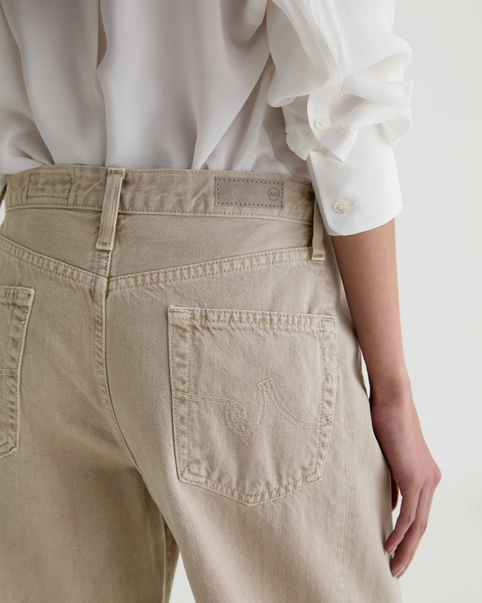 Beige pants with a brand logo on a white background