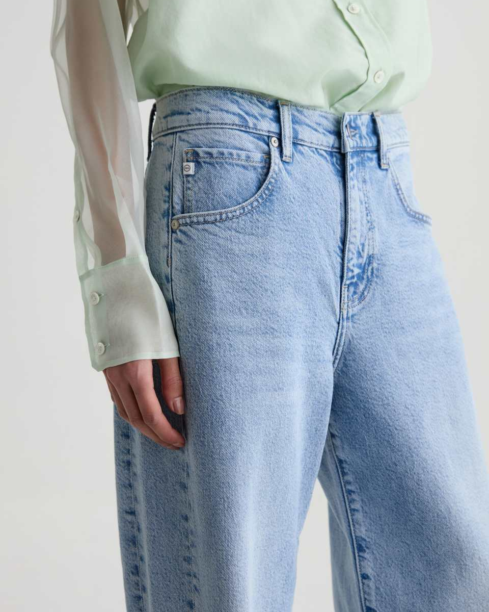 Light blue jeans worn by a person with a light green shirt on a white background