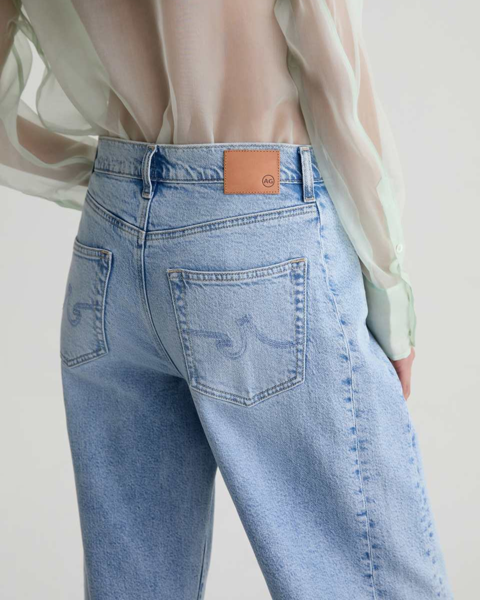 Light blue jeans with a brand logo on the back pocket against a neutral background
