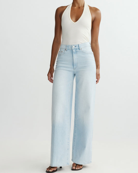 Person wearing light blue jeans and a white tank top on a white background