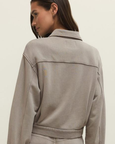 Person wearing a beige jacket and pants on a plain background