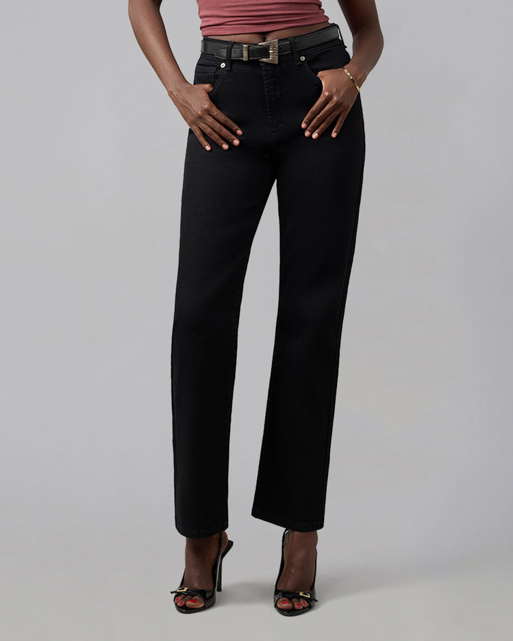 A model wearing black wide-leg cropped jeans with a black belt, paired with a dusty rose top and black high-heeled sandals, photographed against a neutral gray studio background.