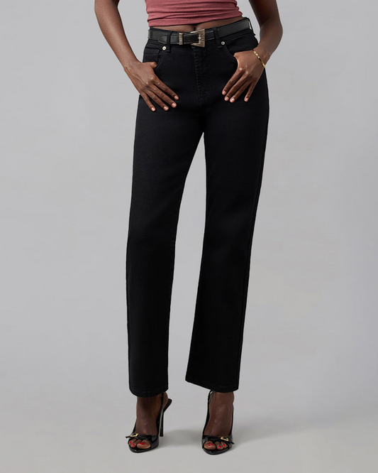 A model wearing black wide-leg cropped jeans with a black belt, paired with a dusty rose top and black high-heeled sandals, photographed against a neutral gray studio background.