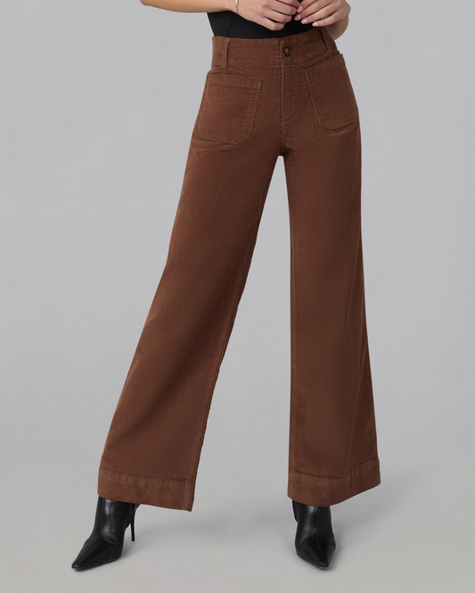 A person wearing high-waisted, wide-leg brown pants with black pointed-toe heeled boots, shown from the waist down against a plain light gray studio background.