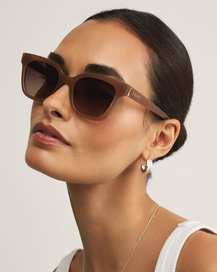 Woman wearing brown sunglasses with a neutral background
