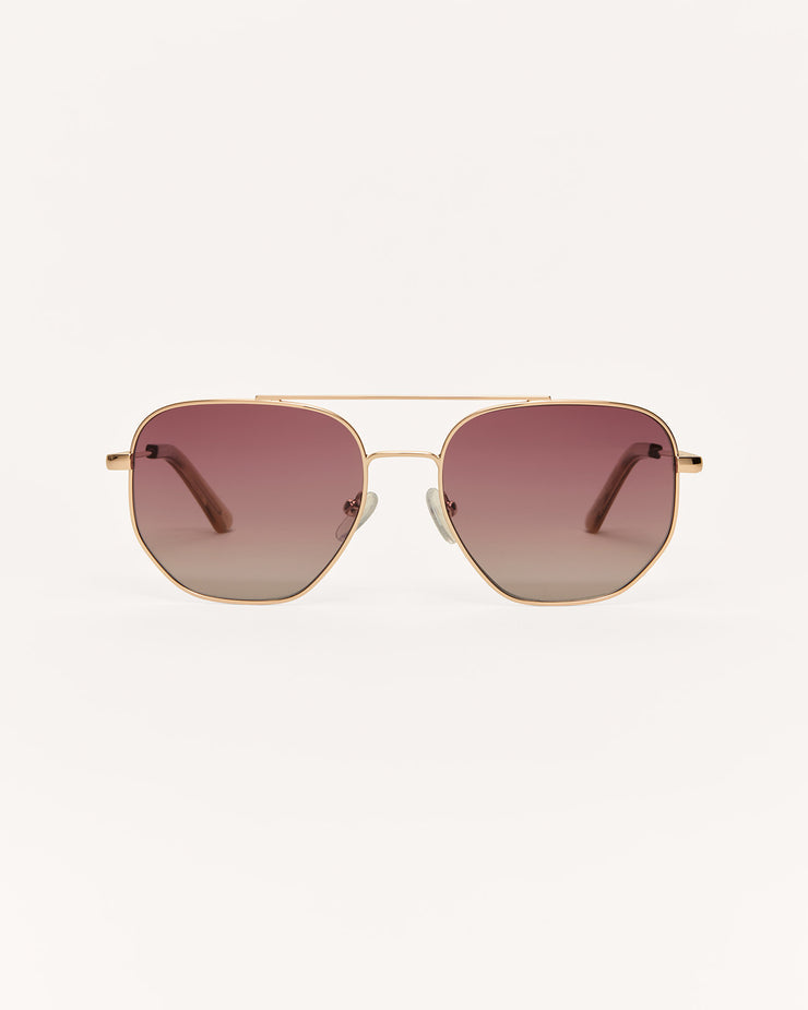 Gold-framed sunglasses with pink gradient lenses on a white background