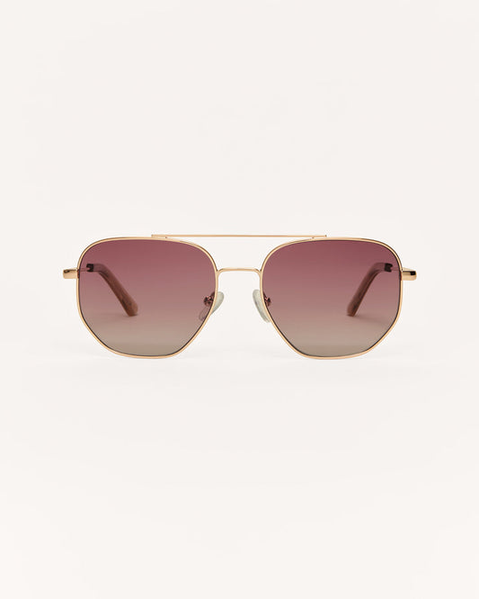 Gold-framed sunglasses with pink gradient lenses on a white background