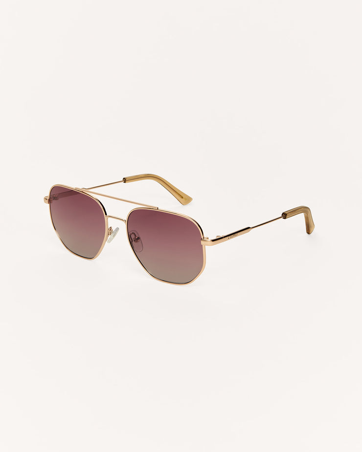 Gold-framed sunglasses with gradient lenses on a white background