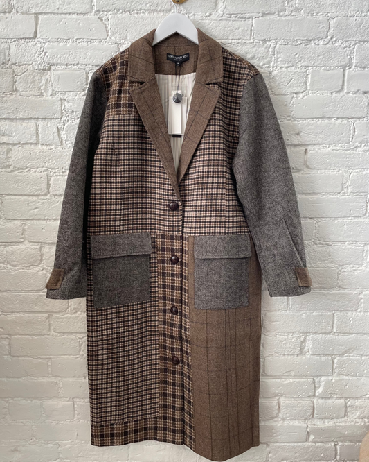 Plaid coat with gray and brown pattern on a white brick wall background