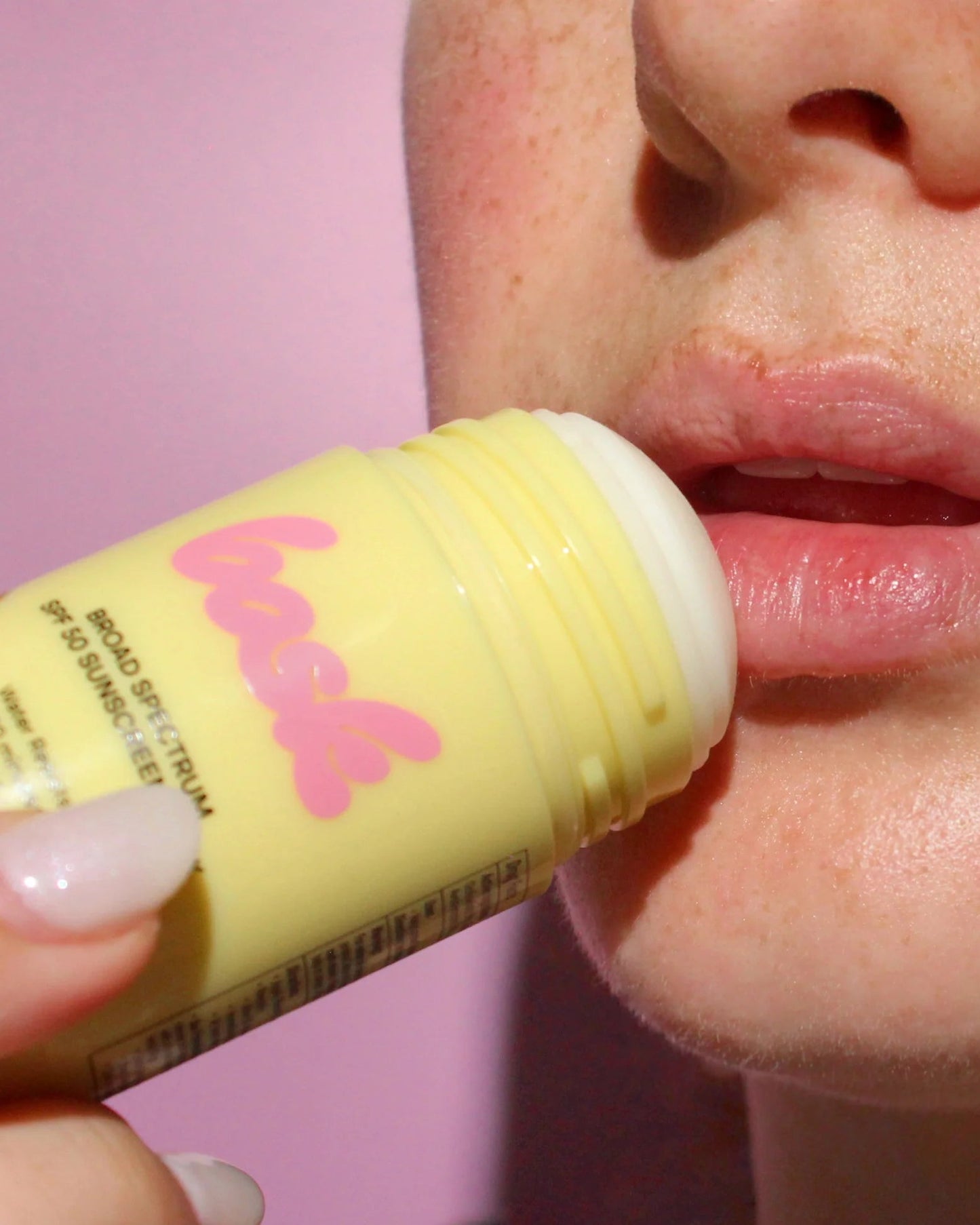 Person applying a yellow lip balm labeled 'Flash' to their lips against a pink background.