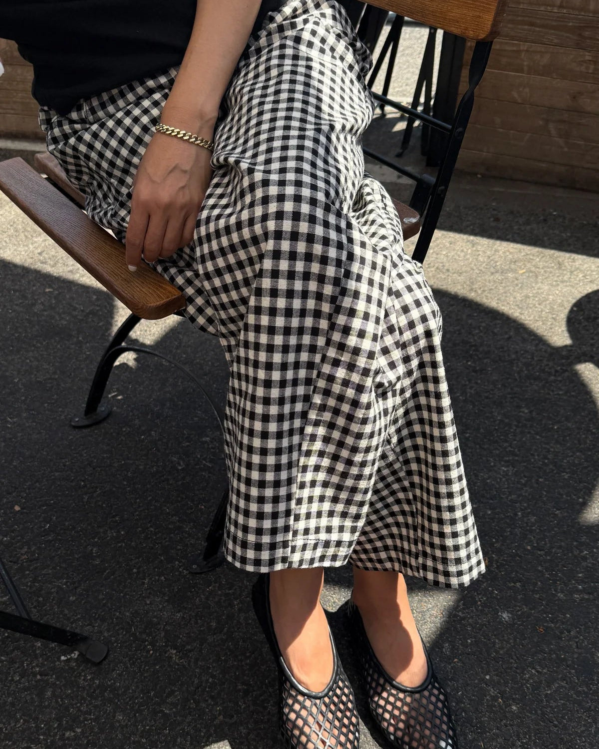 Person wearing a black and white checkered skirt sitting on a chair.