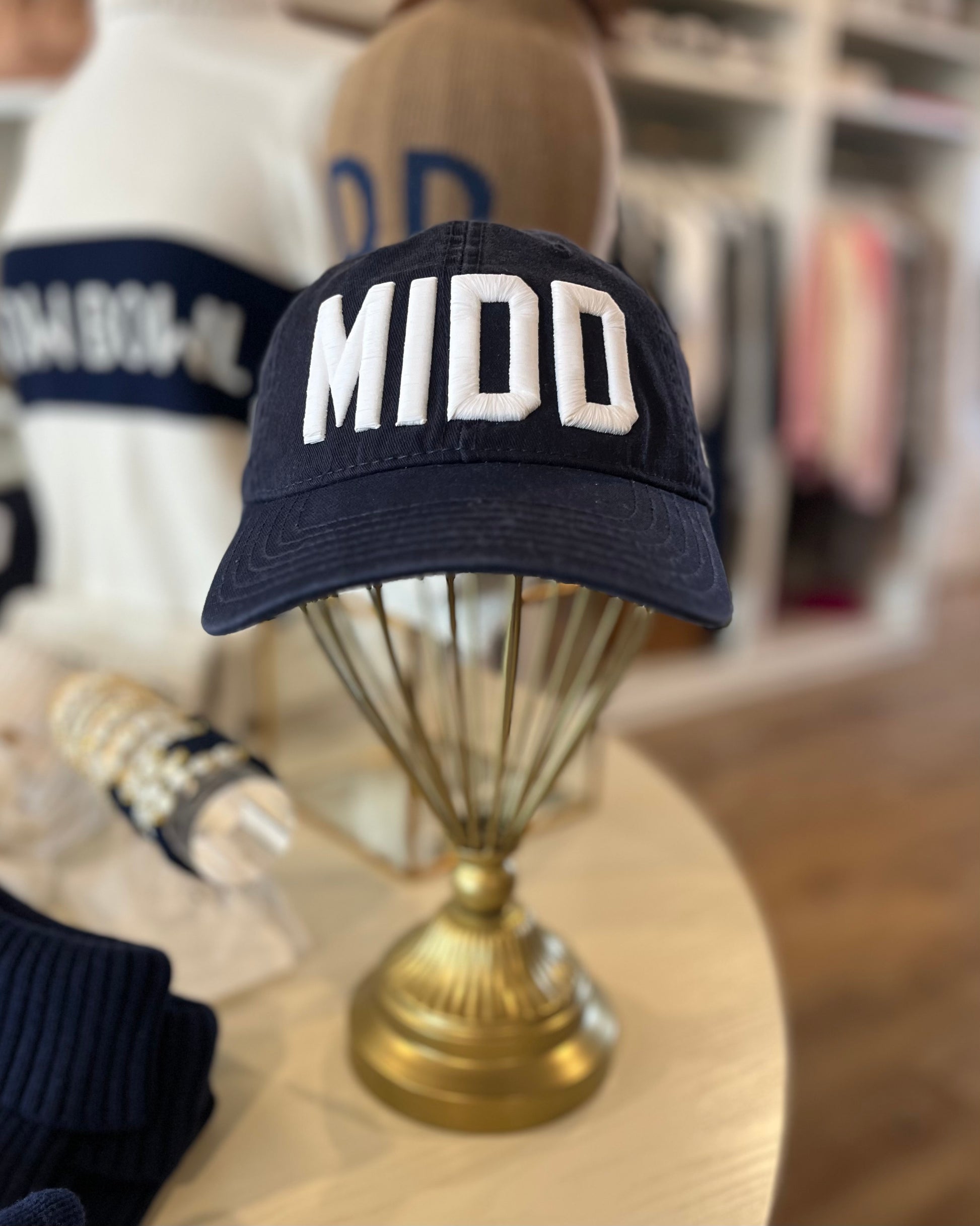 Image of Middlebury College MIDD Navy hat with white stitching sitting on a table