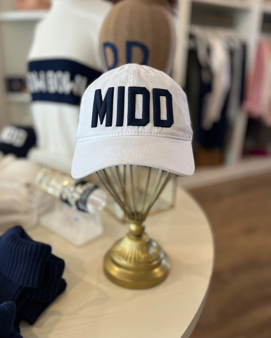 Image Of Middlebury College MIDD hat in White/Navy stitch color sitting on a table