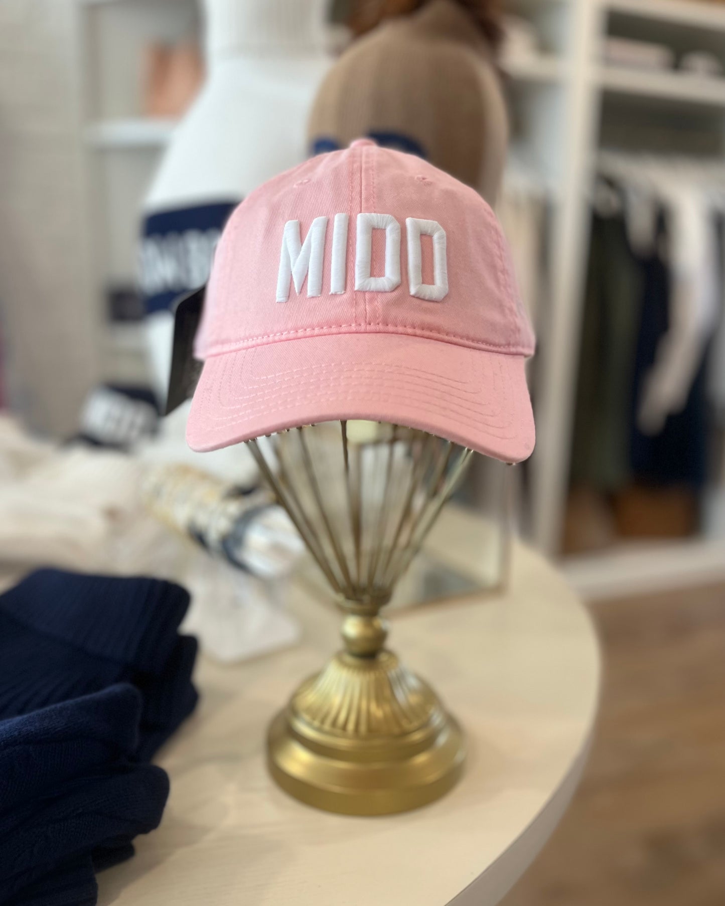 Image of Middlebury College MIDD pink hat with white stitch sitting on a table 