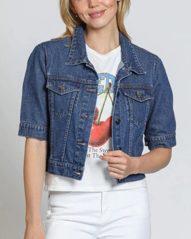 Person wearing a blue denim jacket over a white t-shirt with a graphic design on a plain background