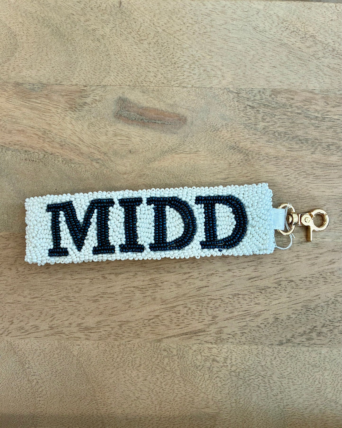 Beaded keychain with 'MIDD' on a wooden surface