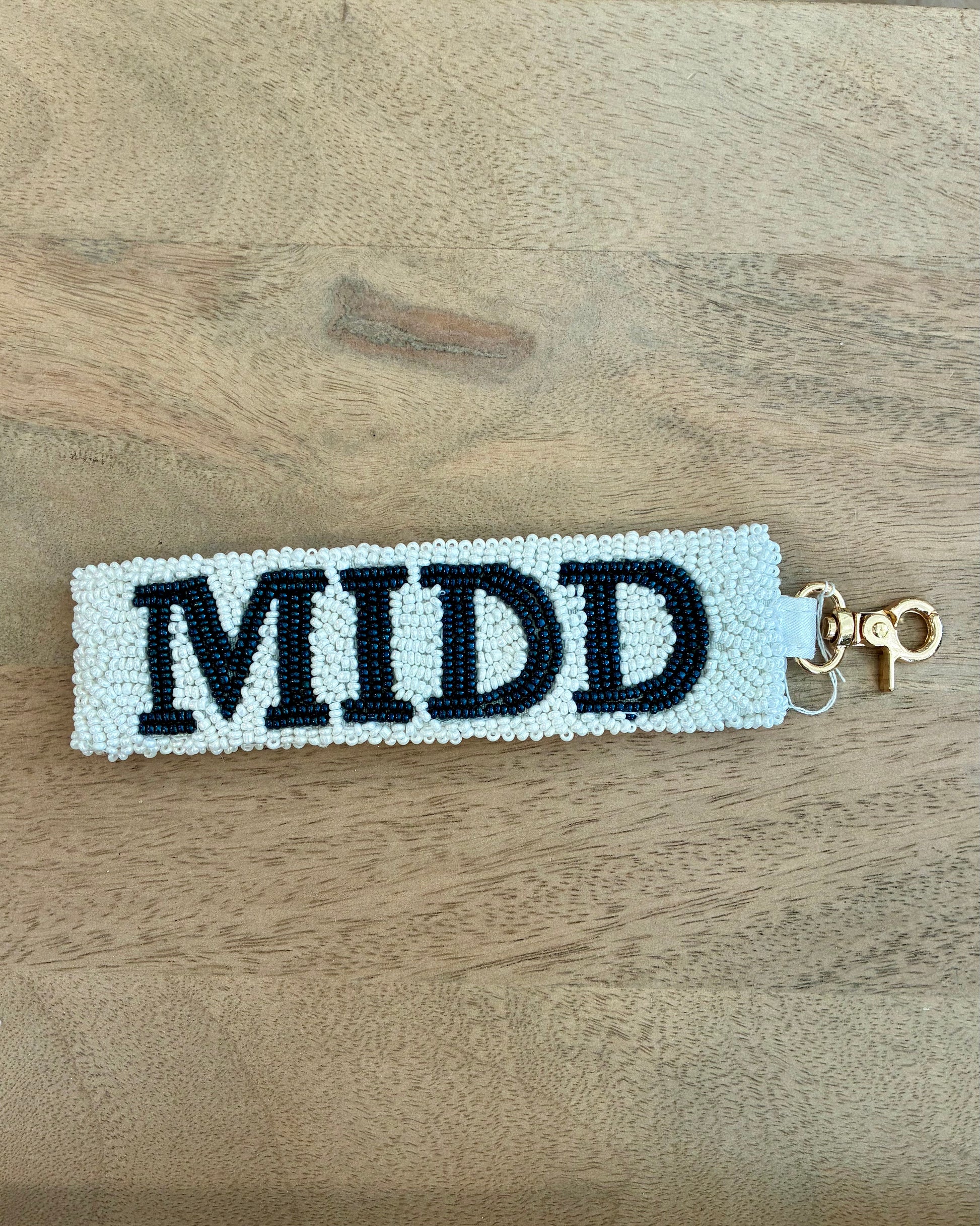 Beaded keychain with 'MIDD' on a wooden surface