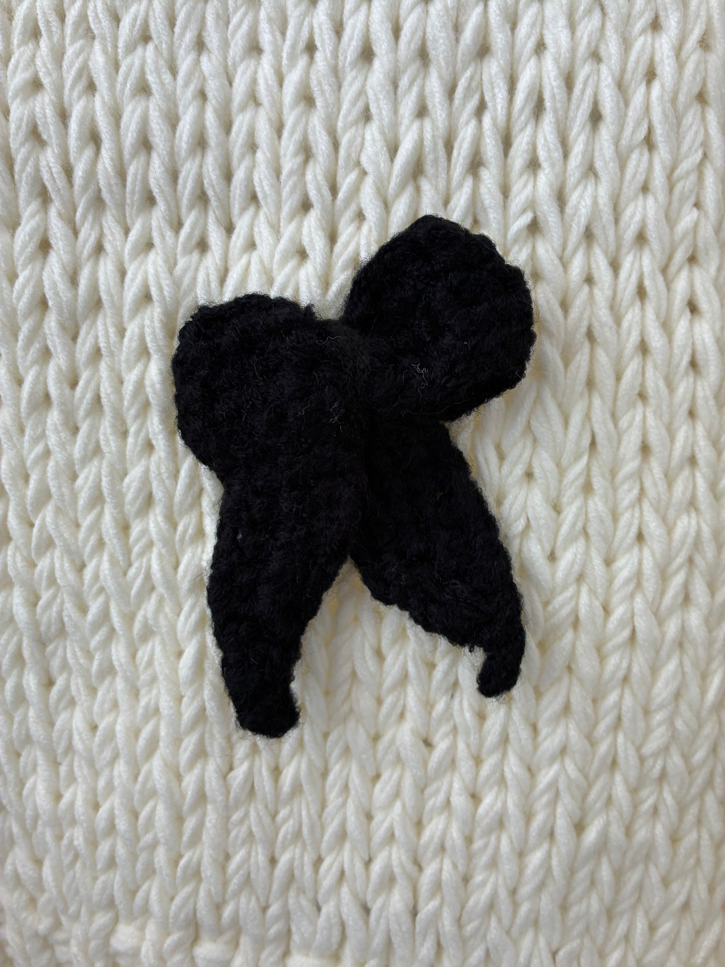 black knit bow on a white cardigan background