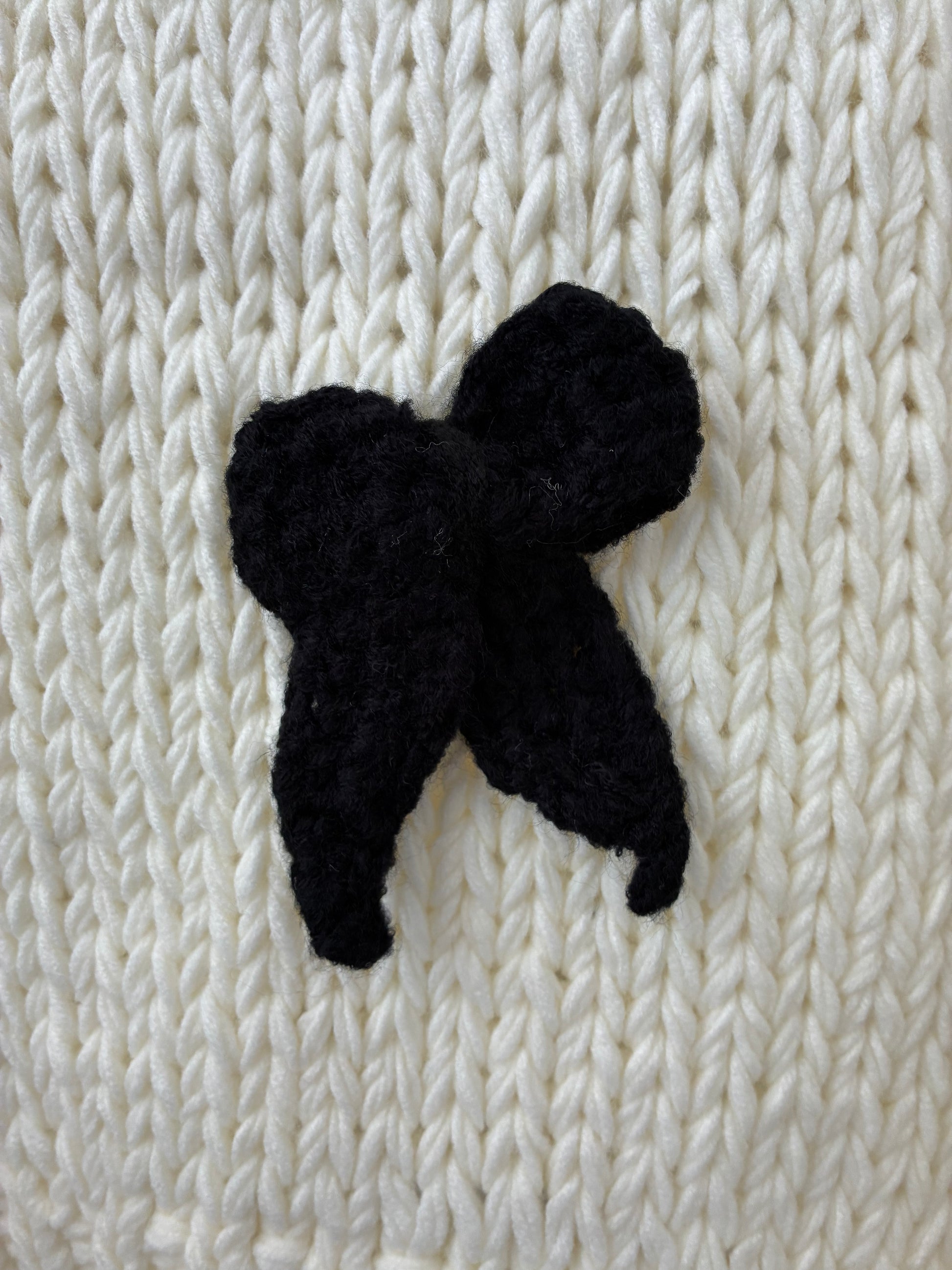 black knit bow on a white cardigan background