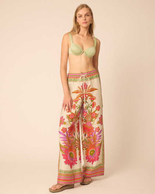 Woman wearing a light green bra and floral wide-leg pants on a beige background