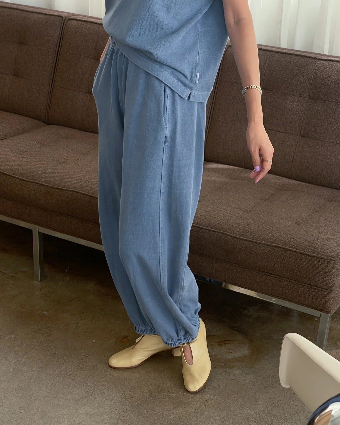 Person wearing blue pants standing in a room with a brown couch.