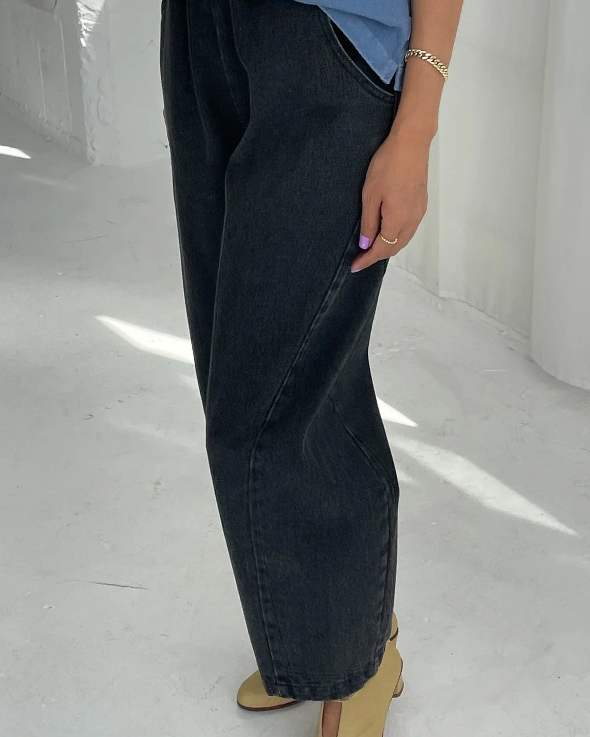 Person wearing dark jeans and a blue top on a white floor.