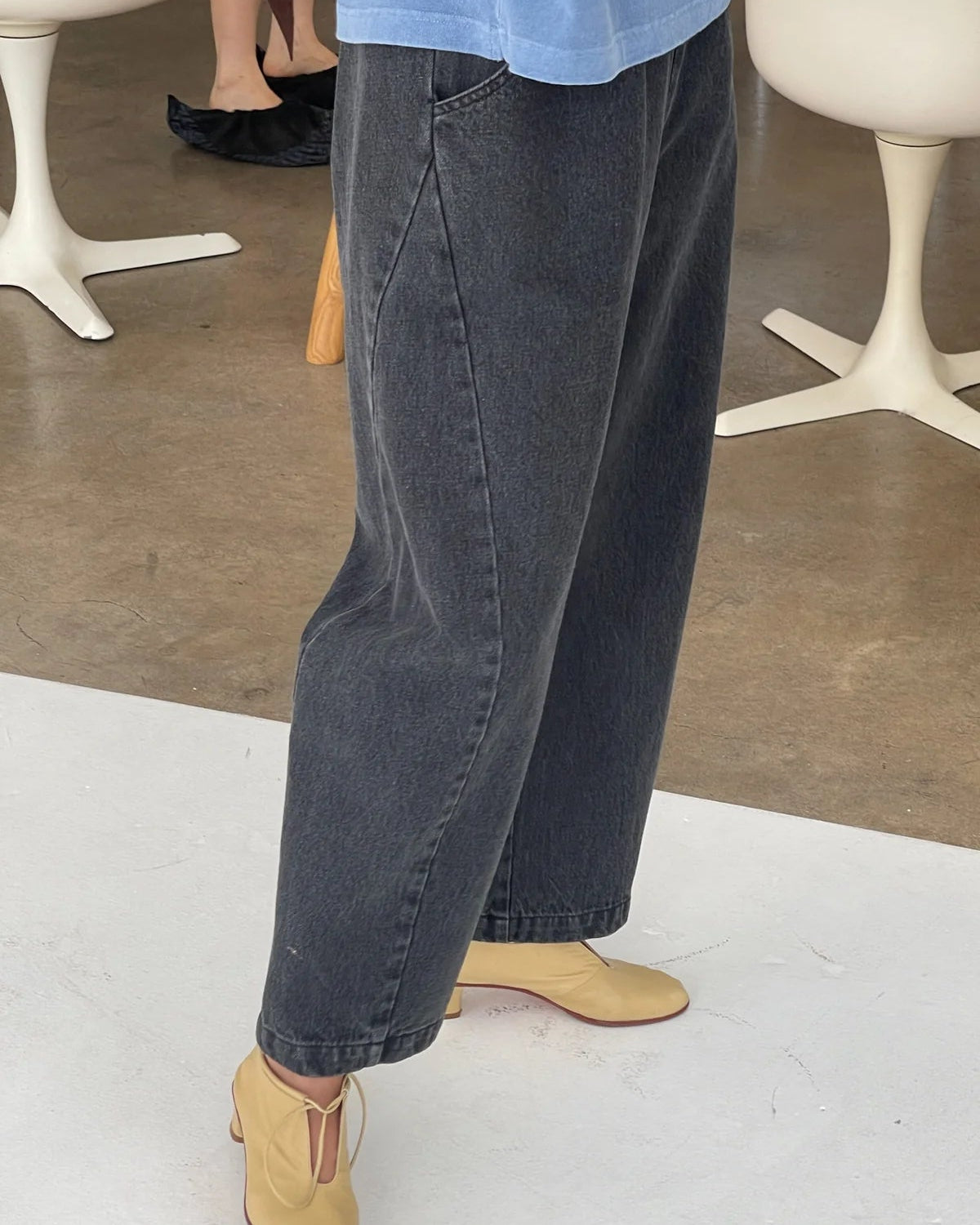 Person wearing black jeans and beige shoes in a minimal indoor setting