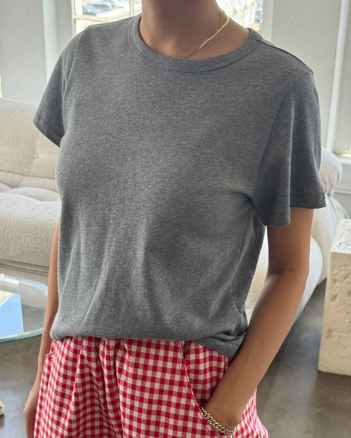 Person wearing a gray t-shirt and red checkered pants in a living room.