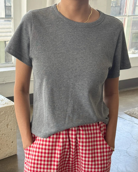 Person wearing a gray t-shirt and red checkered pants indoors.