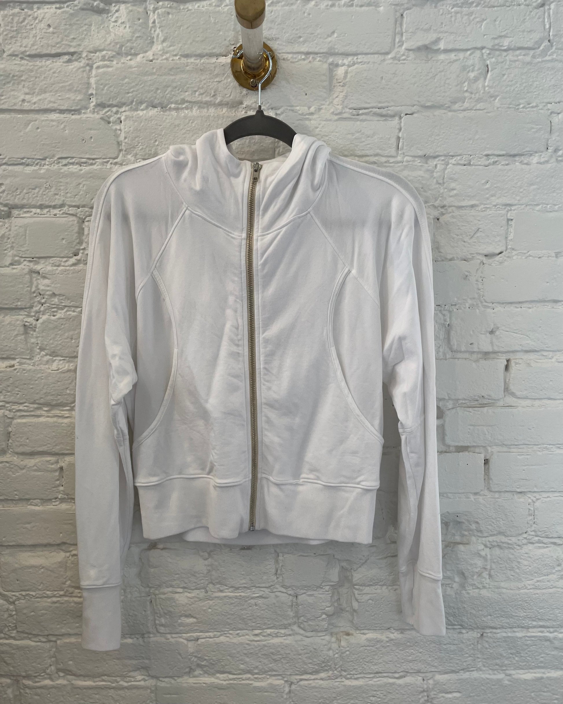 White jacket on a hanger against a light gray brick wall