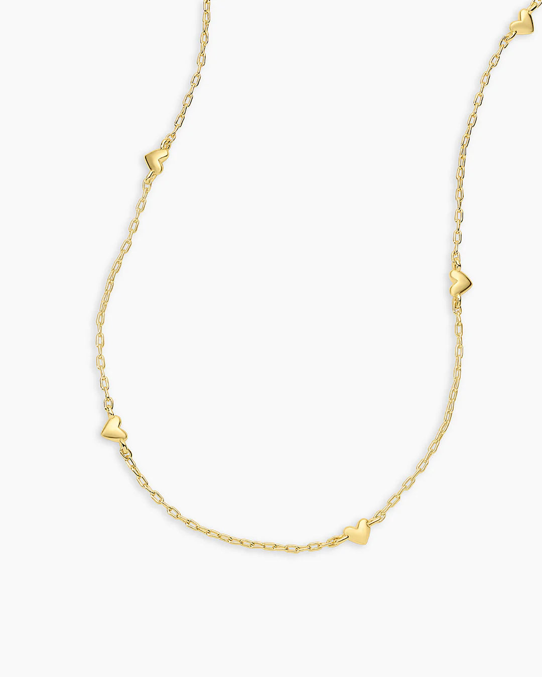 Gold necklace with heart-shaped pendants on a white background