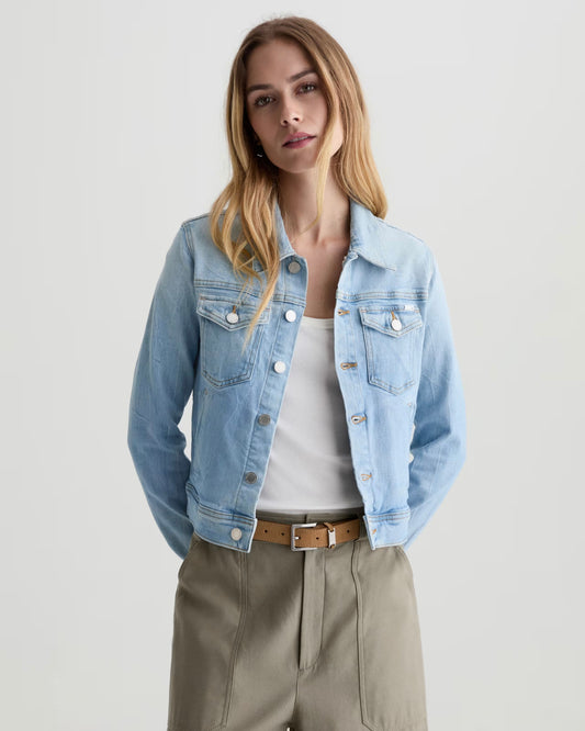 Woman wearing a denim jacket with green trousers in front of a white background