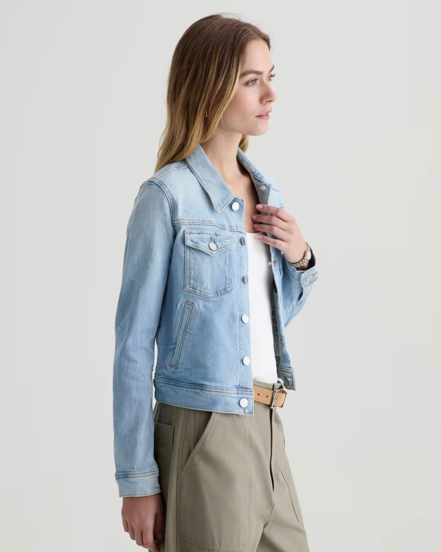 Woman wearing a light blue denim jacket on a plain background