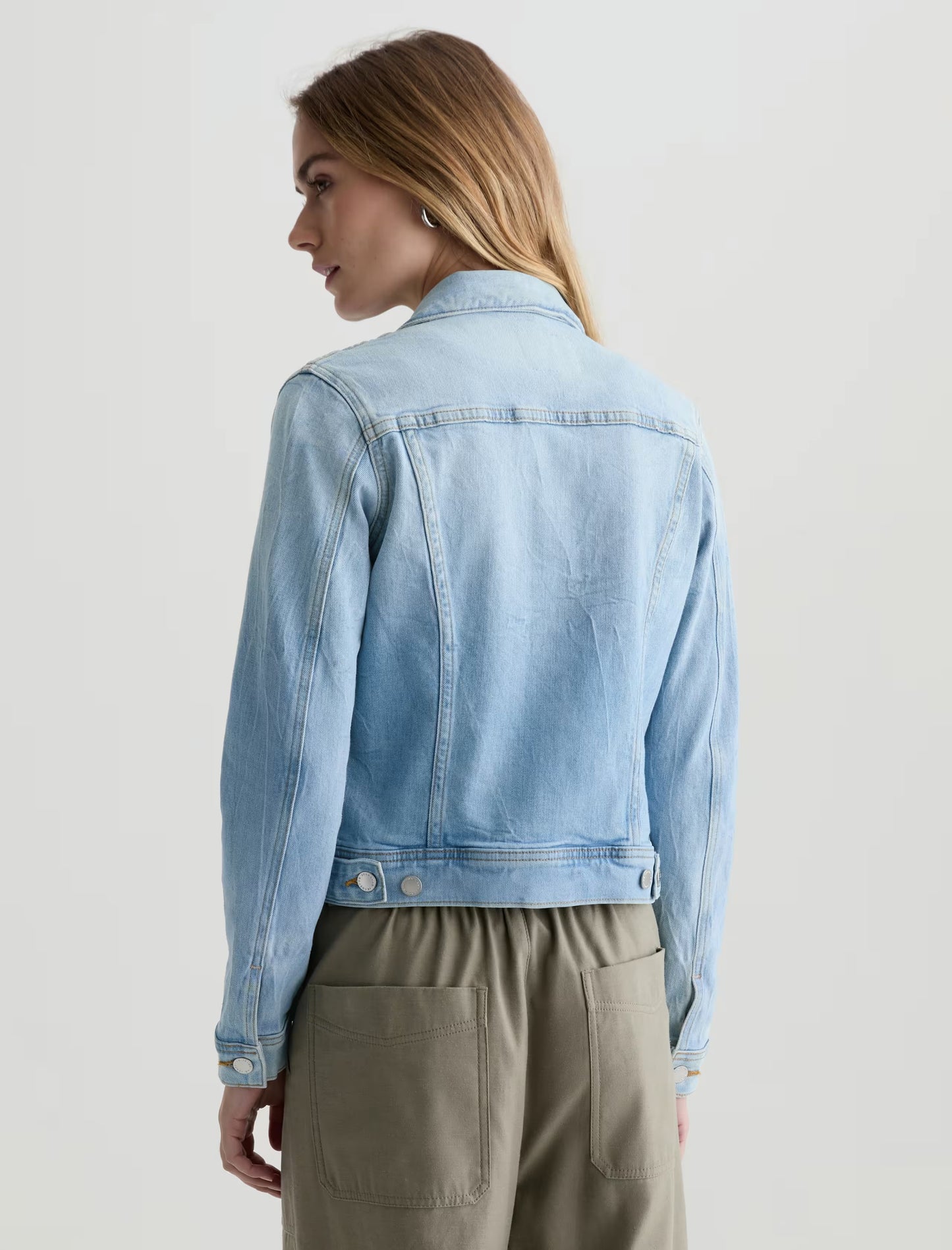 Woman wearing a light blue denim jacket on a plain background