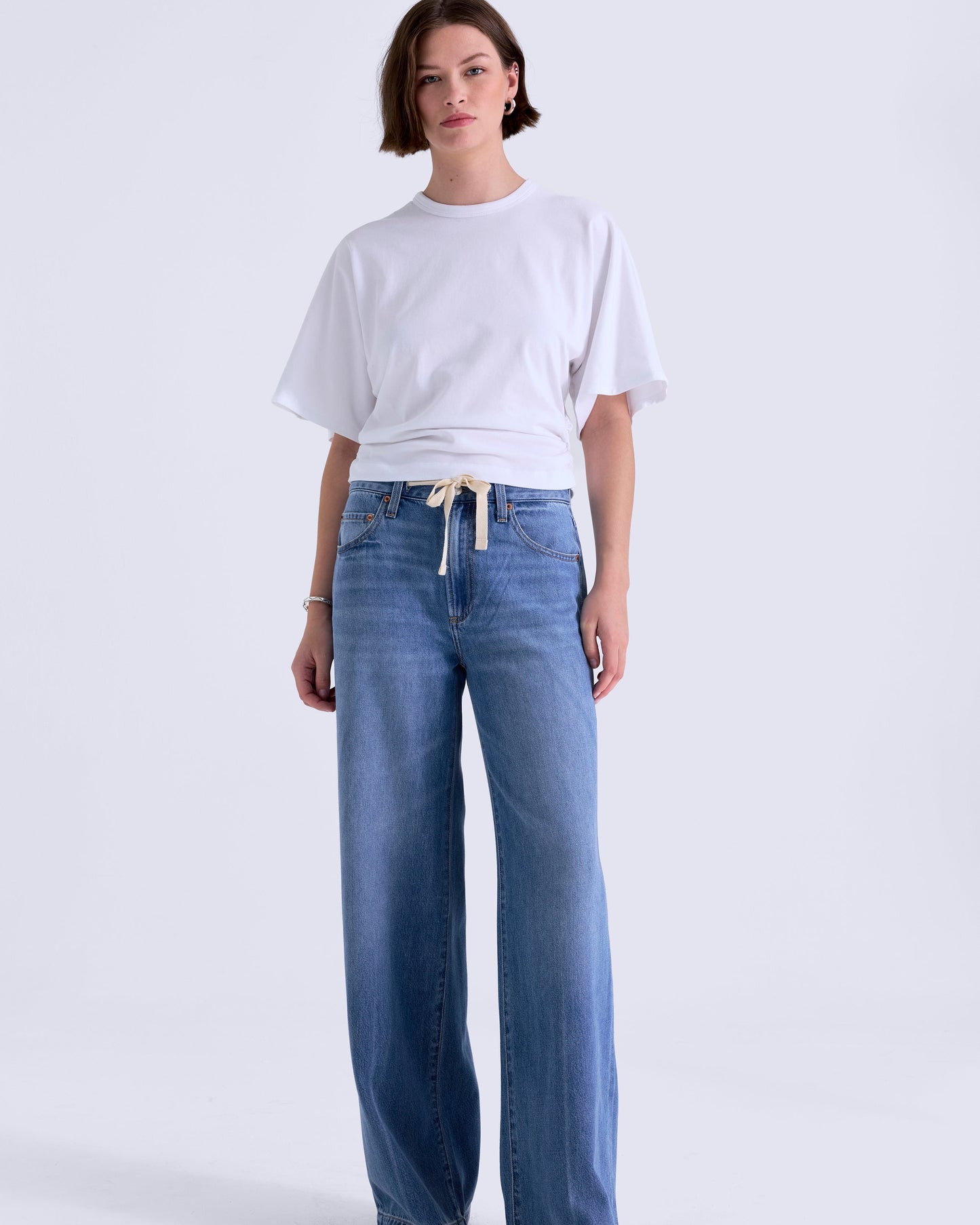 Woman wearing a white t-shirt and blue jeans on a white background