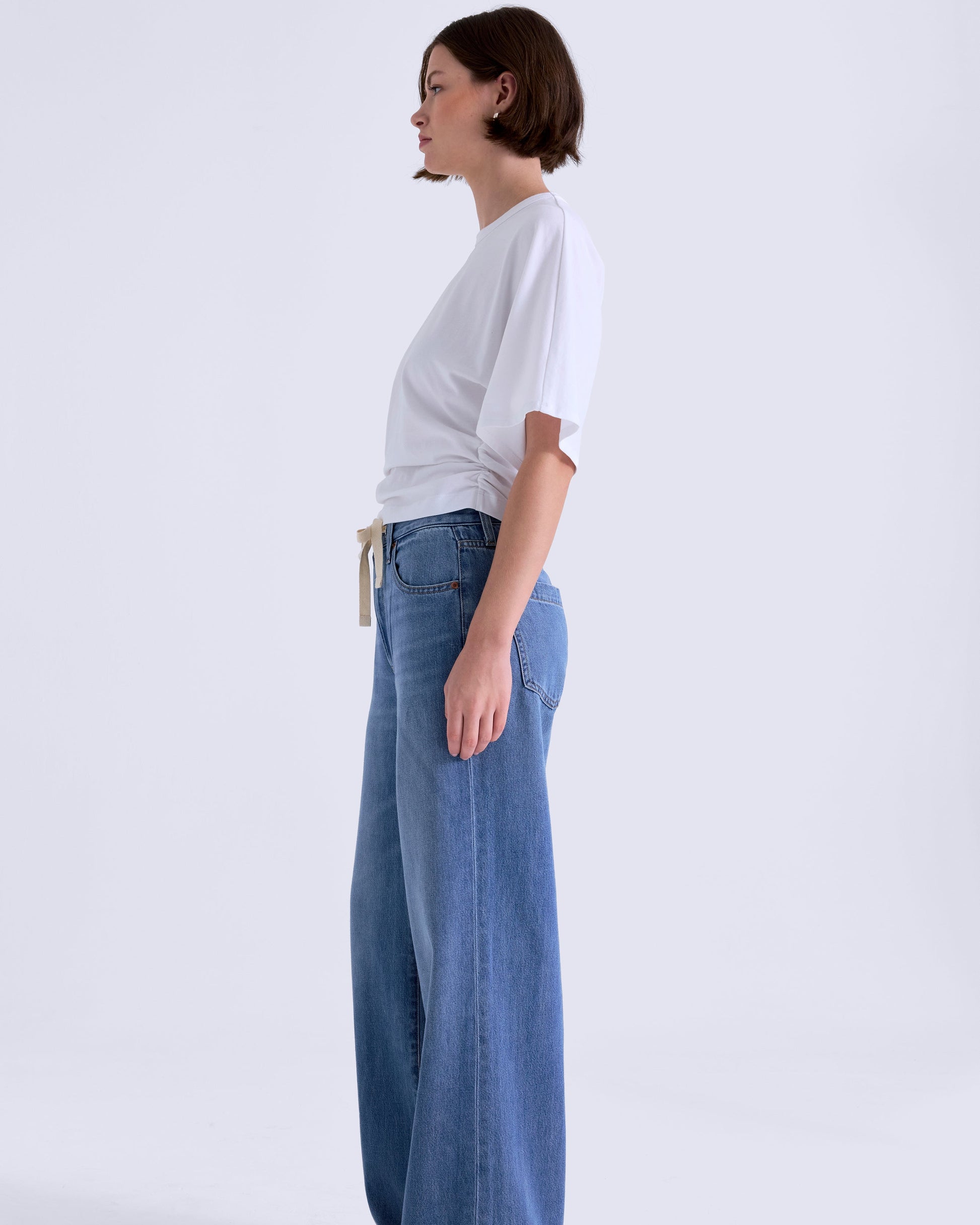 Person wearing a white t-shirt and blue jeans on a white background