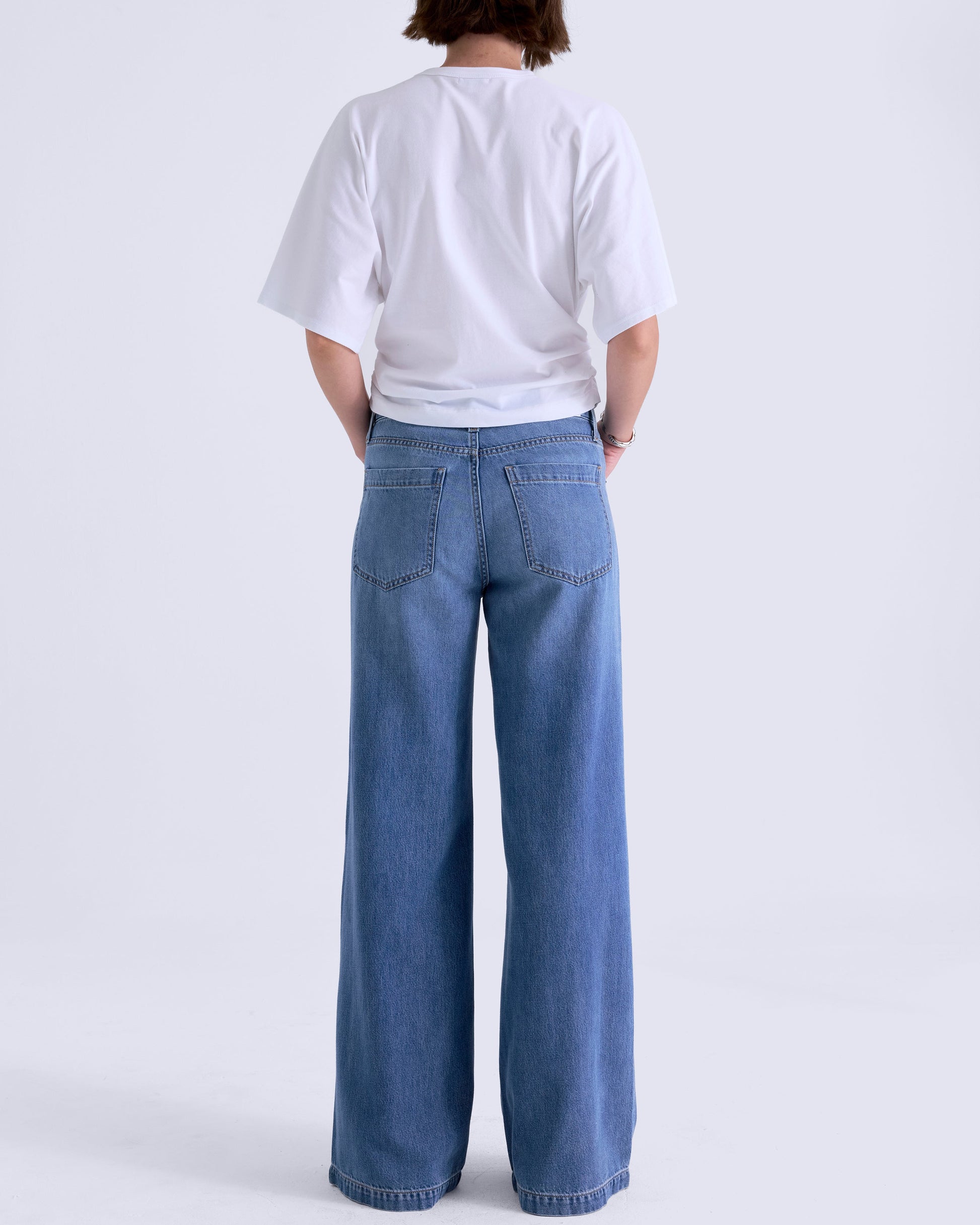 Person wearing a white t-shirt and blue jeans on a white background