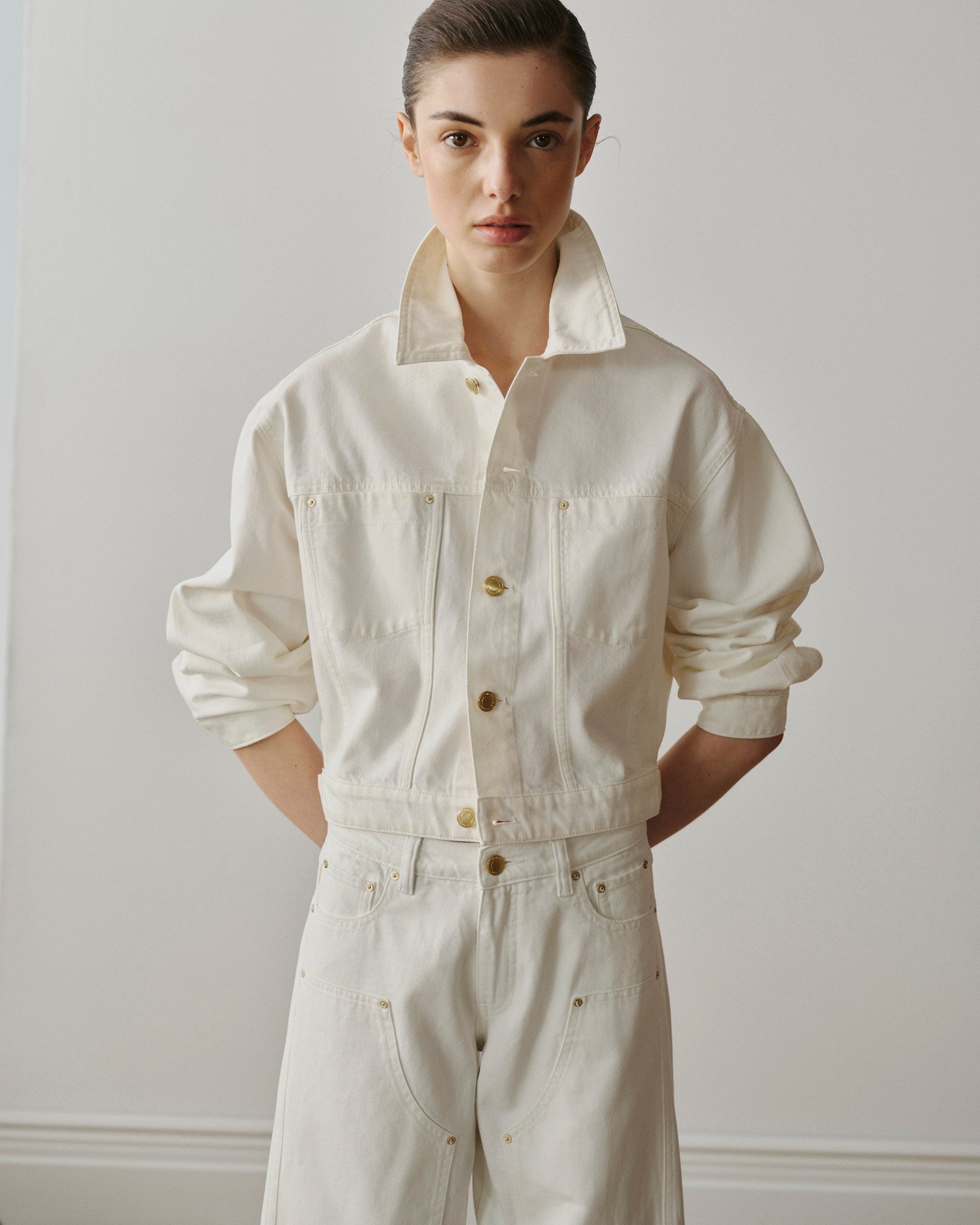 Person wearing a white jumpsuit against a plain background