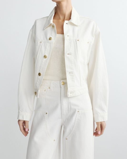 Person wearing a white denim jacket and pants on a light gray background